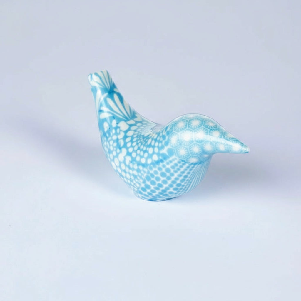 Blue ceramic bird figurine on a light gray background